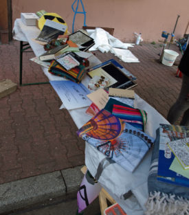 Die Tombola-Preise des Traumschläger Kollektivs. Fotos auf Leinwand und gerahmt,Taschen, Bücher, Zeichenutensilien usw. in mehreren Stapeln aufgebaut und präsentiert